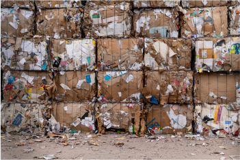 Multiple large recycled cardboard boxes stacked up. with colourful pieces of paper scattered across